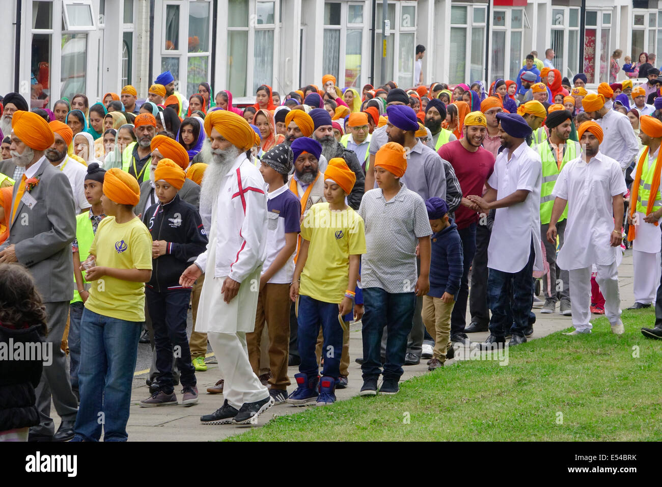 Middlesbrough, Regno Unito. Il 20 luglio, 2014. L annuale Nagar Kirtan Parade celebra la cultura Sikh nel nord-est dell' Inghilterra ha avuto luogo in Middlesbrough Cleveland UK oggi è domenica 20 luglio. Il corteo è guidato da cinque zafferano derubato gli uomini che portano un galleggiante che porta il Guru Granth Sahib i sikh la Sacra Scrittura. Membri della processione è a piedi nudi in ossequio alla scrittura così visualizzato. Essi sono preceduti da spazzatrici pulizia della strada. Questa immagine mostra i sikh ordinaria seguendo il galleggiante sul retro della sfilata. Credito: Pietro Giordano NE/Alamy Live News Foto Stock