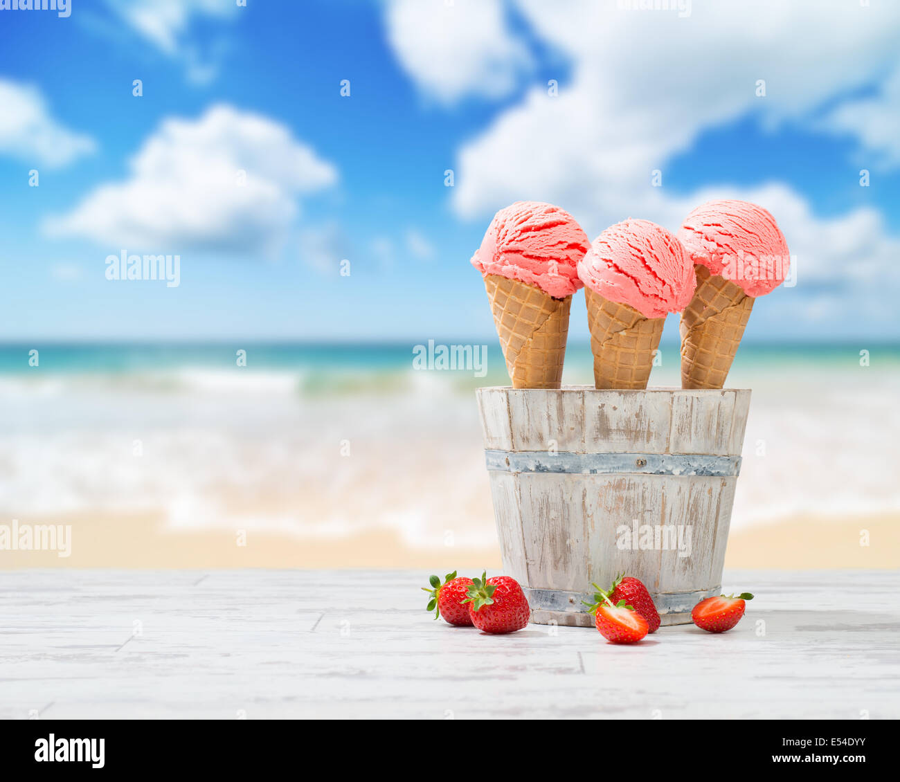 Fragola gelati con frutta in legno decking con spiaggia blur sullo sfondo Foto Stock