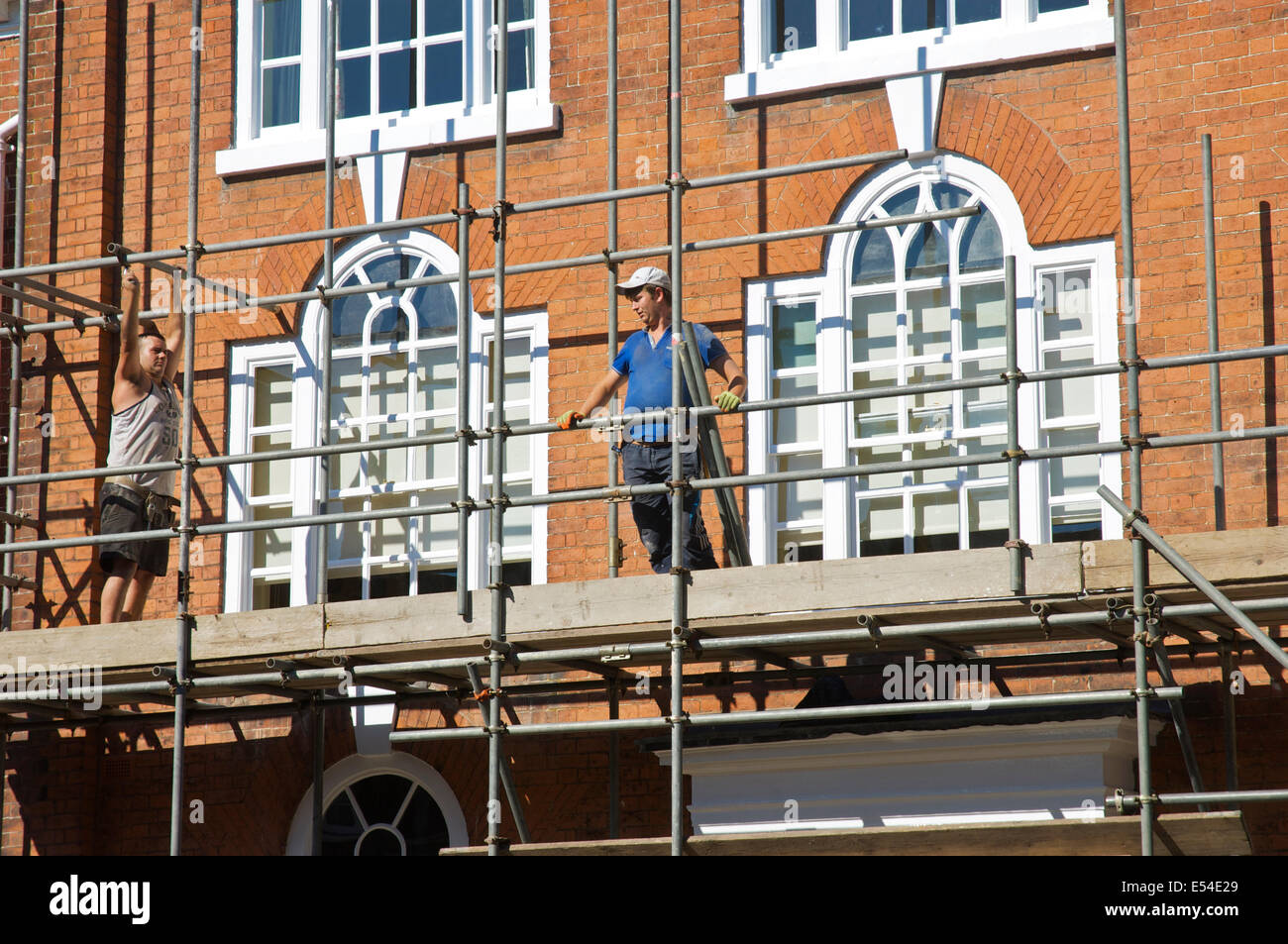 Due uomini lo smantellamento ponteggi su edificio Georgiano, Ludlow, Shropshire, Inghilterra, Regno Unito Foto Stock
