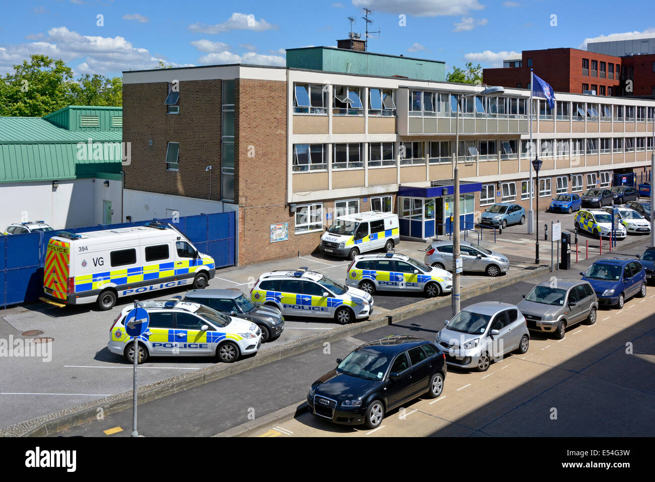Vista dall'alto guardando verso il basso le auto e i furgoni della polizia assortiti parcheggiati all'ingresso dell'edificio degli uffici della stazione di polizia di Basildon, Essex, Inghilterra, Regno Unito Foto Stock