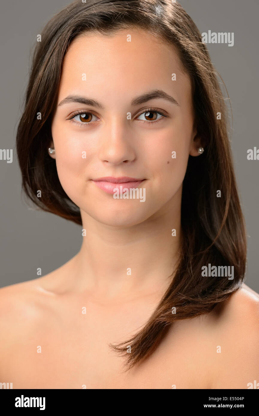 Bella ragazza adolescente cosmetici per la cura della pelle bruna ritratto su grigio Foto Stock