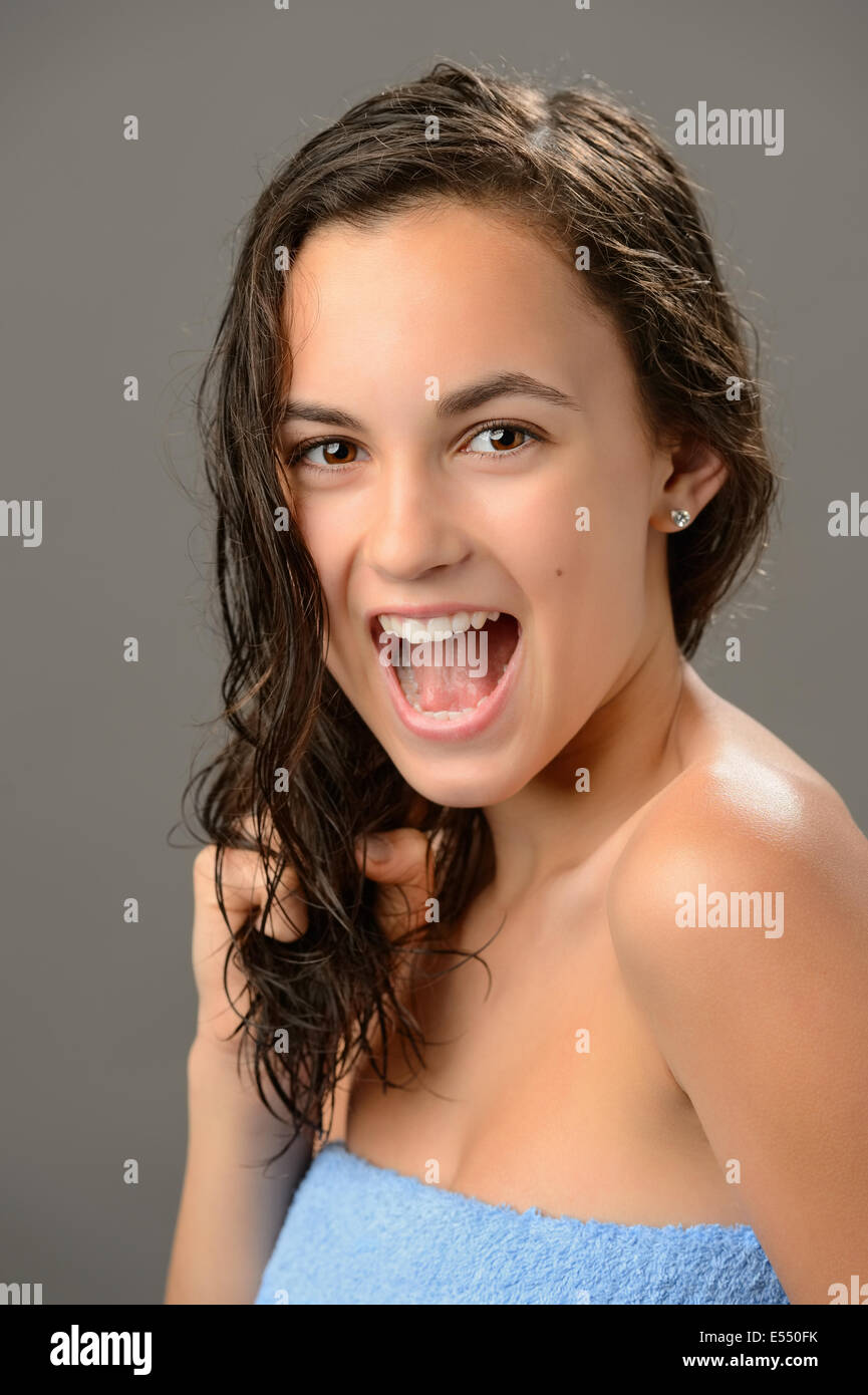 Allegro ragazza adolescente tirando i capelli umidi care brunette su sfondo grigio Foto Stock
