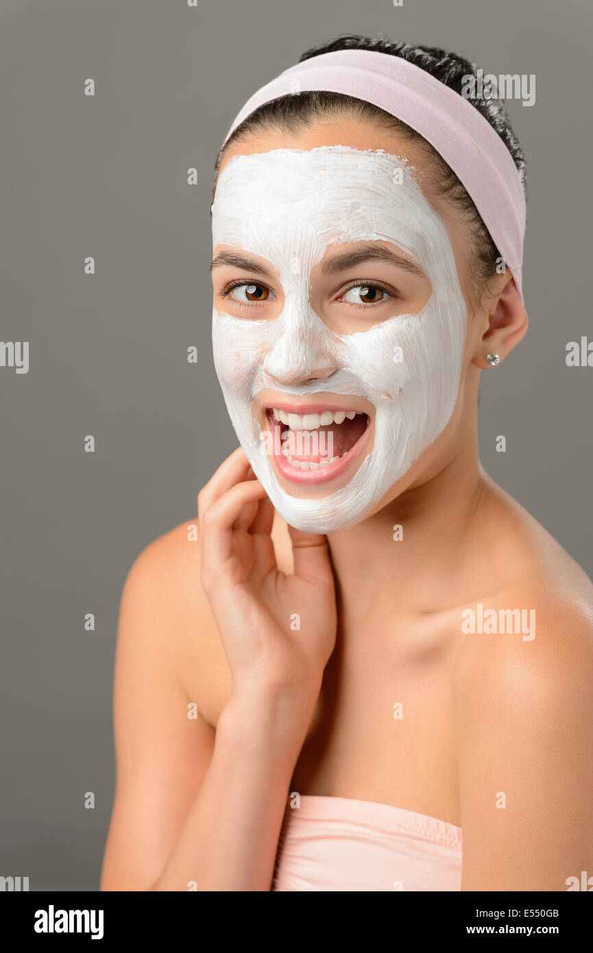 Bellezza adolescente sorridente ragazza bianco maschera facciale su sfondo grigio Foto Stock