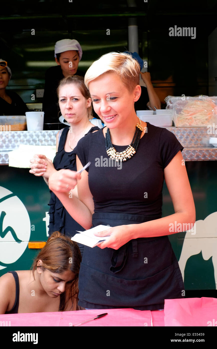 Sorridente giovane femmina prendendo gli ordini a Southsea food fair festival 2014 England Regno Unito Foto Stock