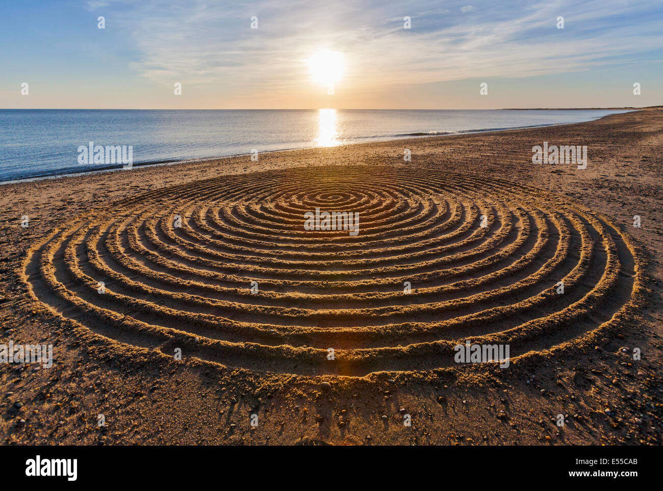 Arte di sabbia sulla spiaggia con l'oceano e un tramonto in vista. Foto Stock