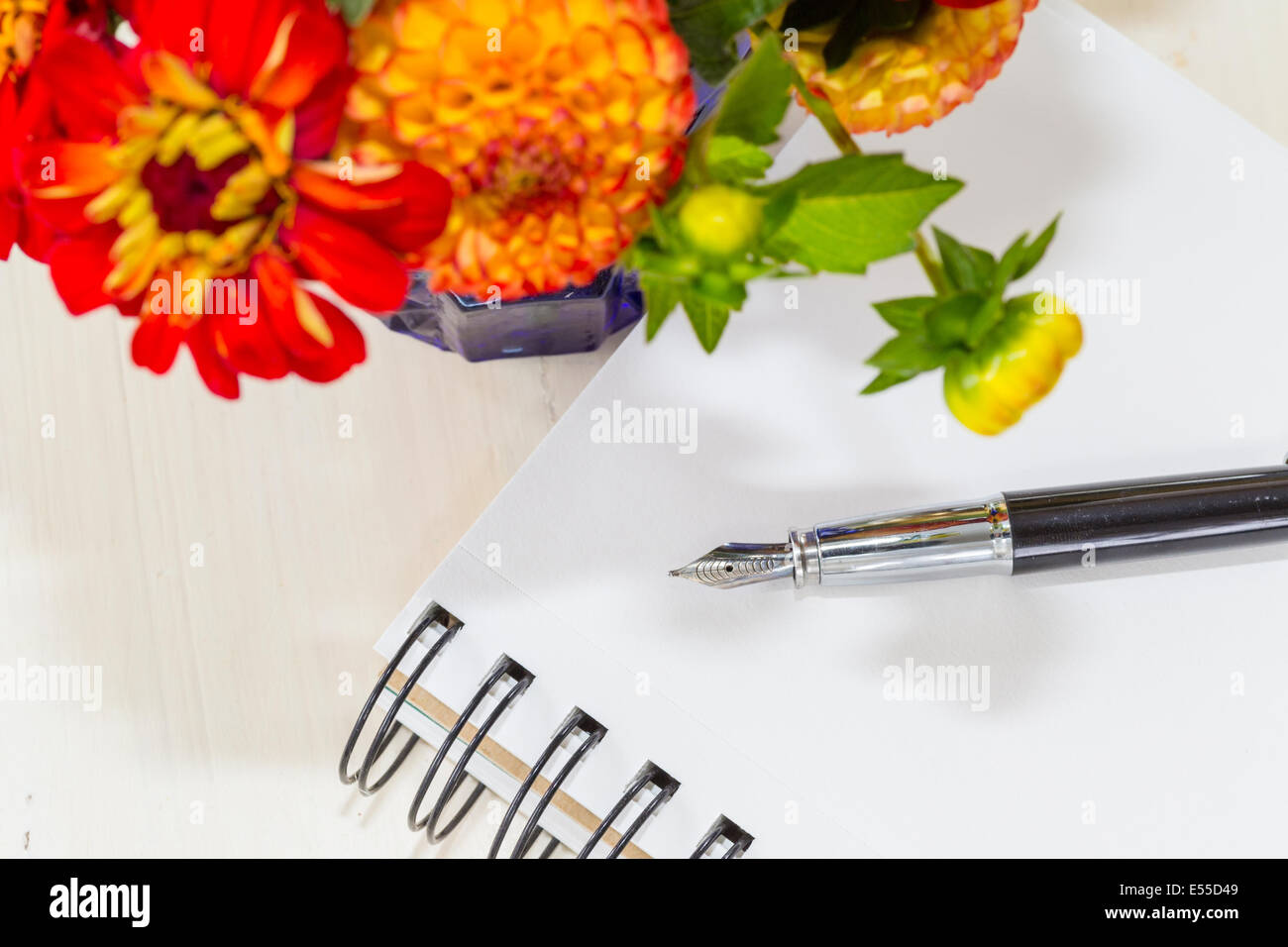 Home caduta di stile bouquet con fiori da giardino a fianco di un notebook e la penna stilografica. Foto Stock