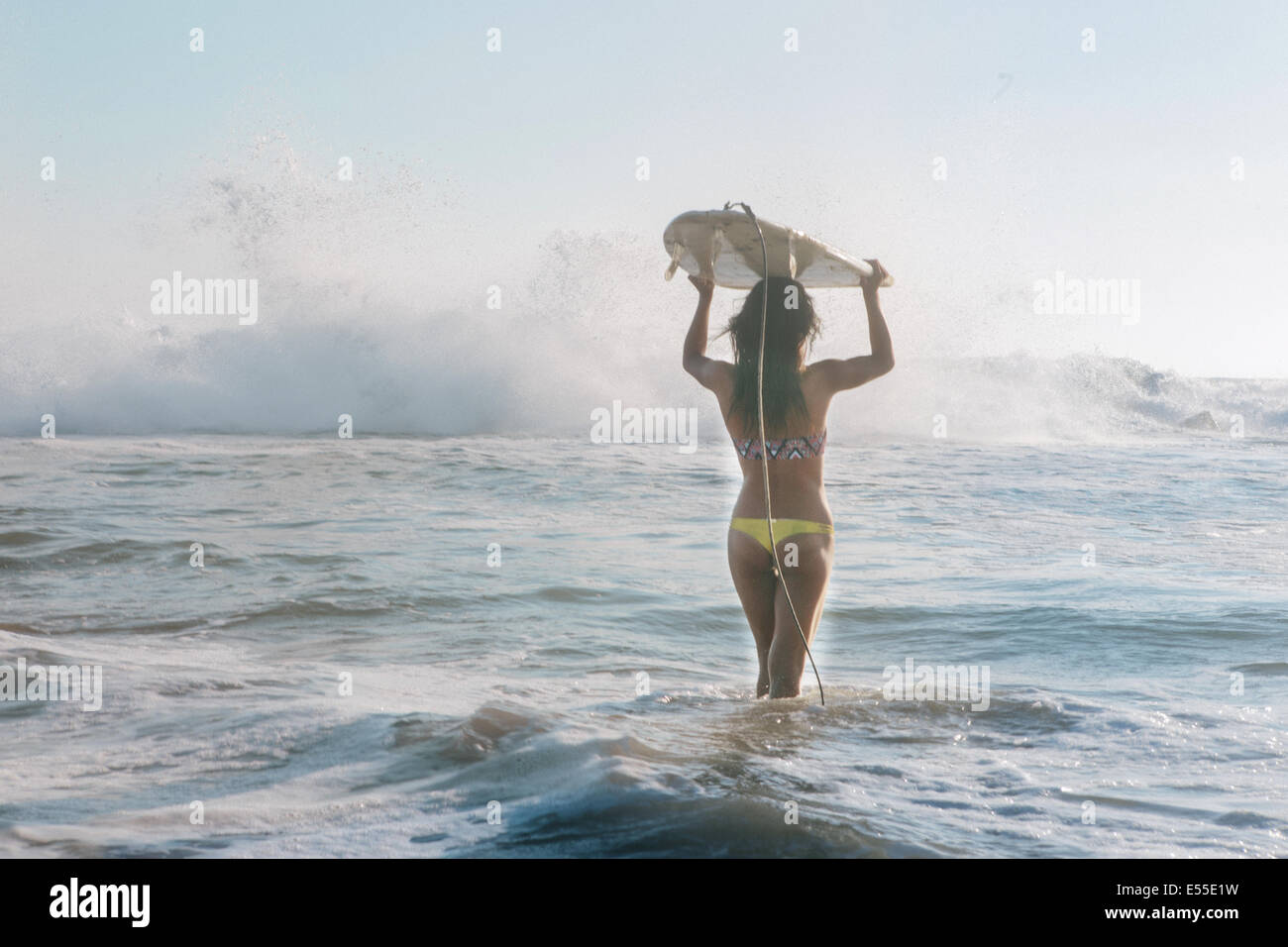 Giovani femmine surfer che trasportano le tavole da surf sulla testa a piedi verso le onde del mare Foto Stock