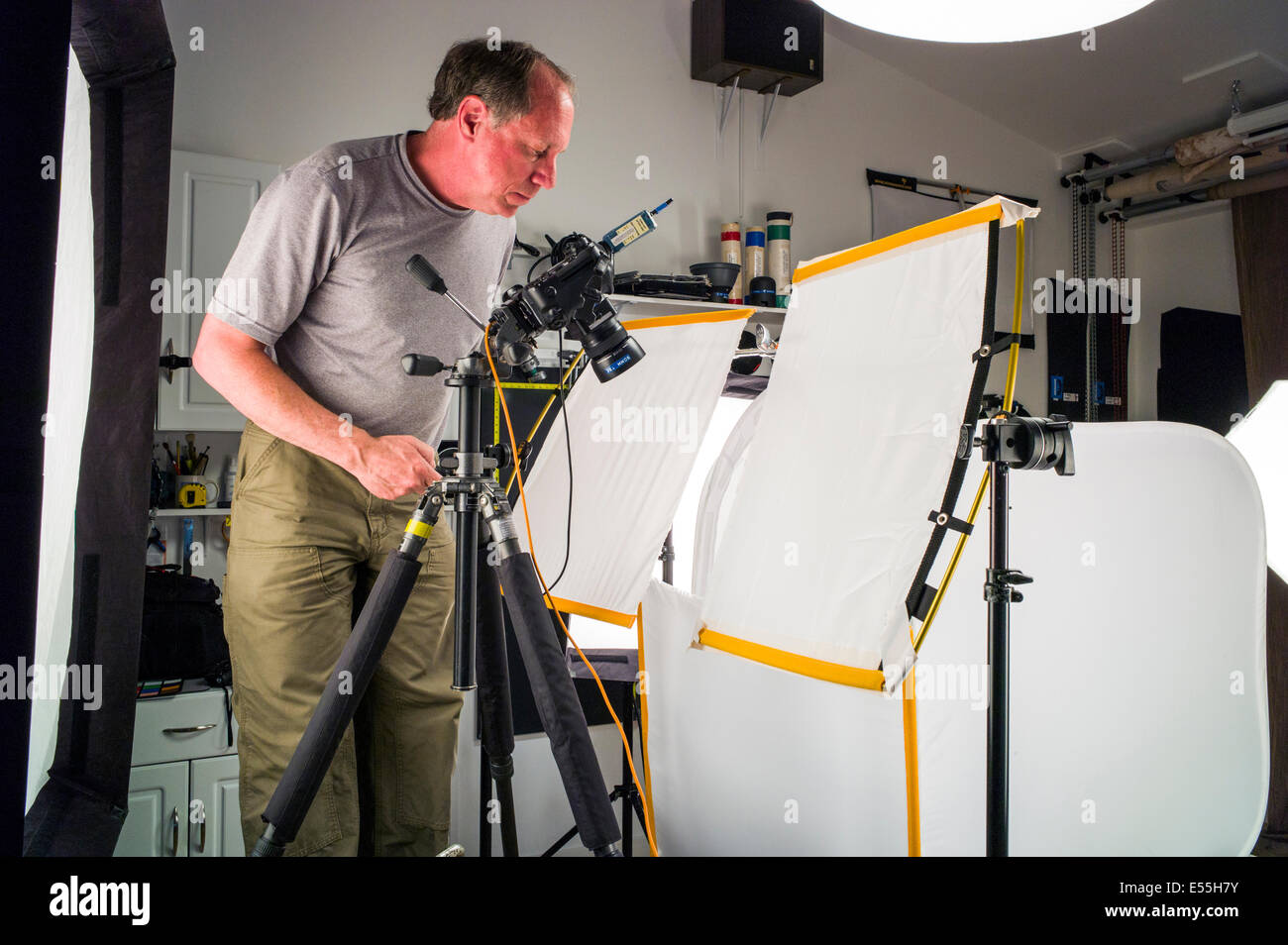 Fotografo lavorando su una fotografia commerciale impostare, compresa l'illuminazione dello sfondo e ingranaggio di presa. Foto Stock