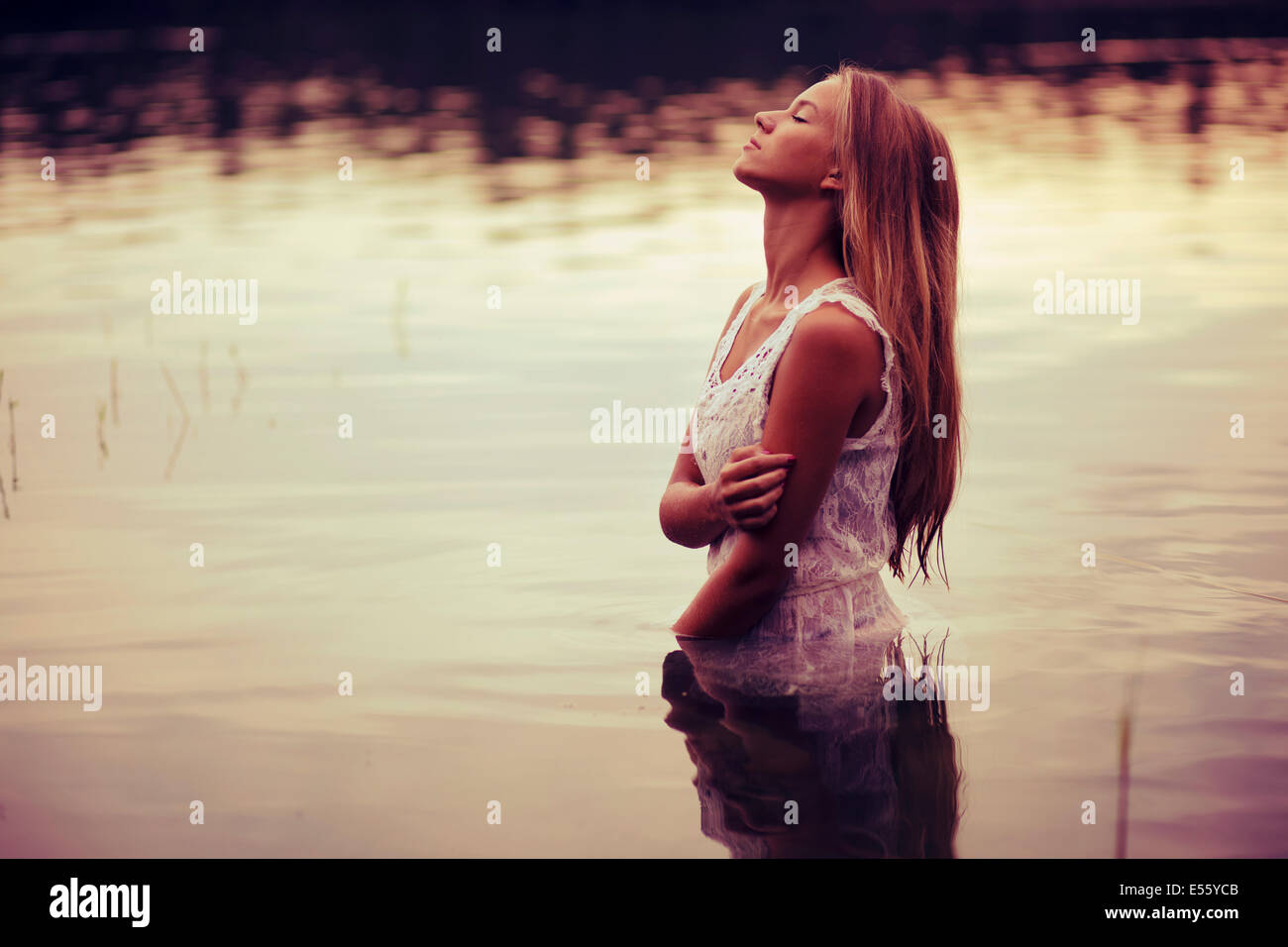 Giovane donna in abito bianco in piedi in acqua Foto Stock