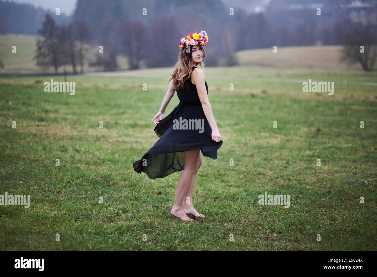 Giovane donna con ghirlanda di fiori danza su un prato Foto Stock