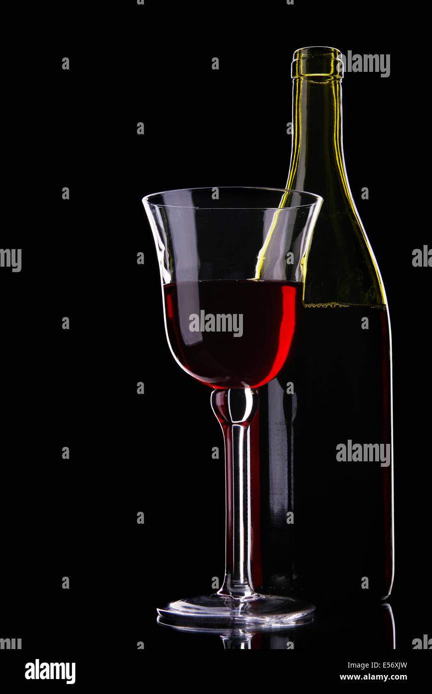 Still-life con bottiglia e bicchiere di vino rosso su sfondo nero Foto Stock
