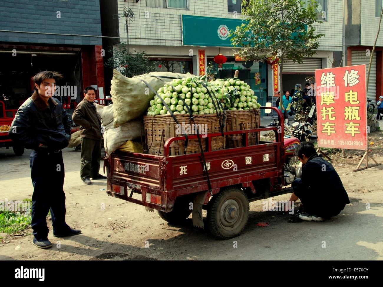 JIA WAN, CINA: agricoltore rende la riparazione per il suo piccolo autocarro riempito con cavolo cinese egli è il trasporto dei mercati locali Foto Stock