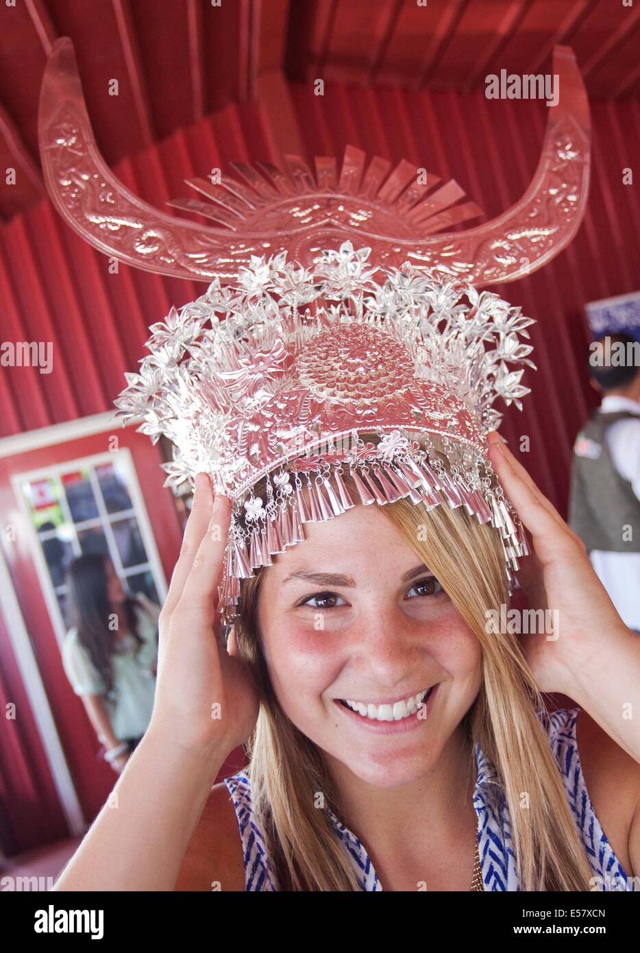 Toronto, Canada. 22 Luglio, 2014. Una donna cerca di indossare un argento ornamento di testa durante il 'colorata Guizhou Exhibition" nella città di Niagara sul Lago Ontario, Canada, 22 luglio 2014. Con artigianato etnico e musica dal sud-ovest della Cina di Guizhou, la mostra ha richiamato centinaia di locale ha visitato il martedì. Credito: Zou Zheng/Xinhua/Alamy Live News Foto Stock