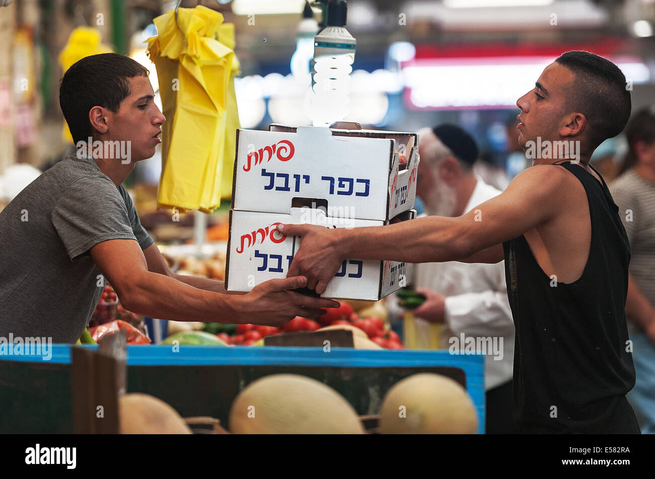 Un fornitore di fornitori e trasferire le casse piene di frutta fresca presso il fornitore stallo al Machane Yehuda Market, Gerusalemme, Israele Foto Stock