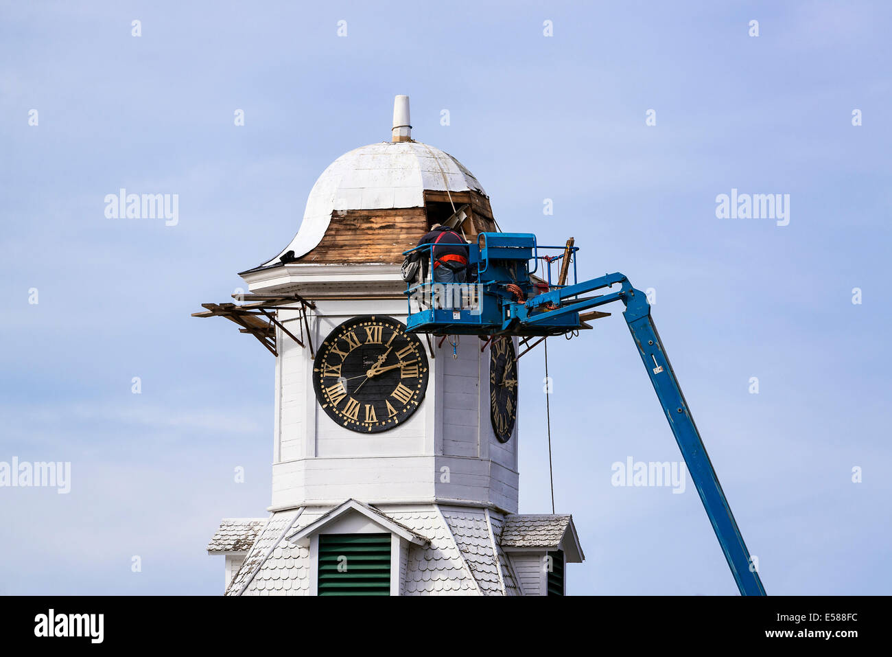 Gli uomini su un cherry picker riparare il ripristino del tetto della torre civica dell'orologio, Weston, Vermont, USA Foto Stock