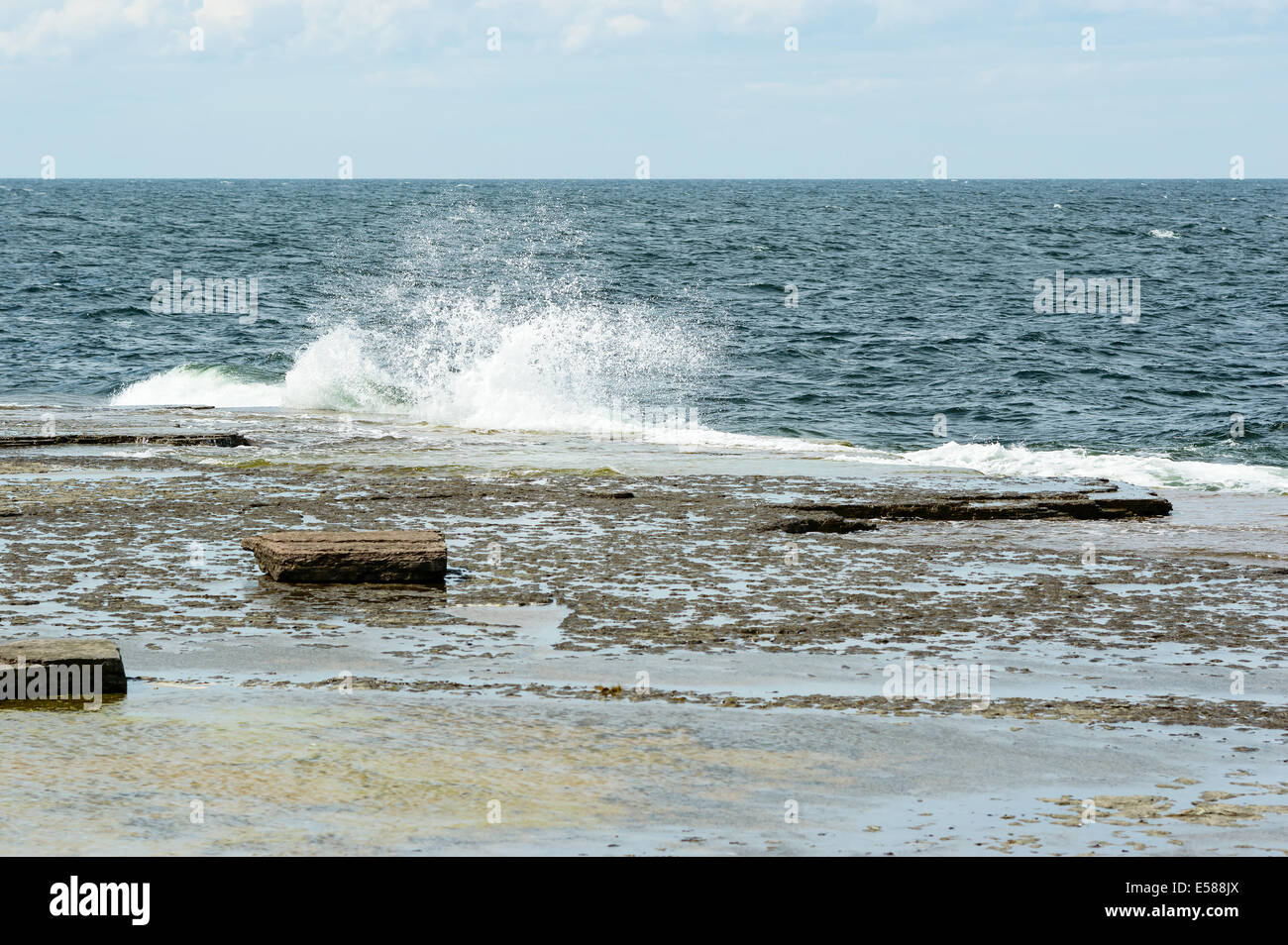 Piccole onde estive di colpire calcare spiaggia mentre la rottura. Foto Stock