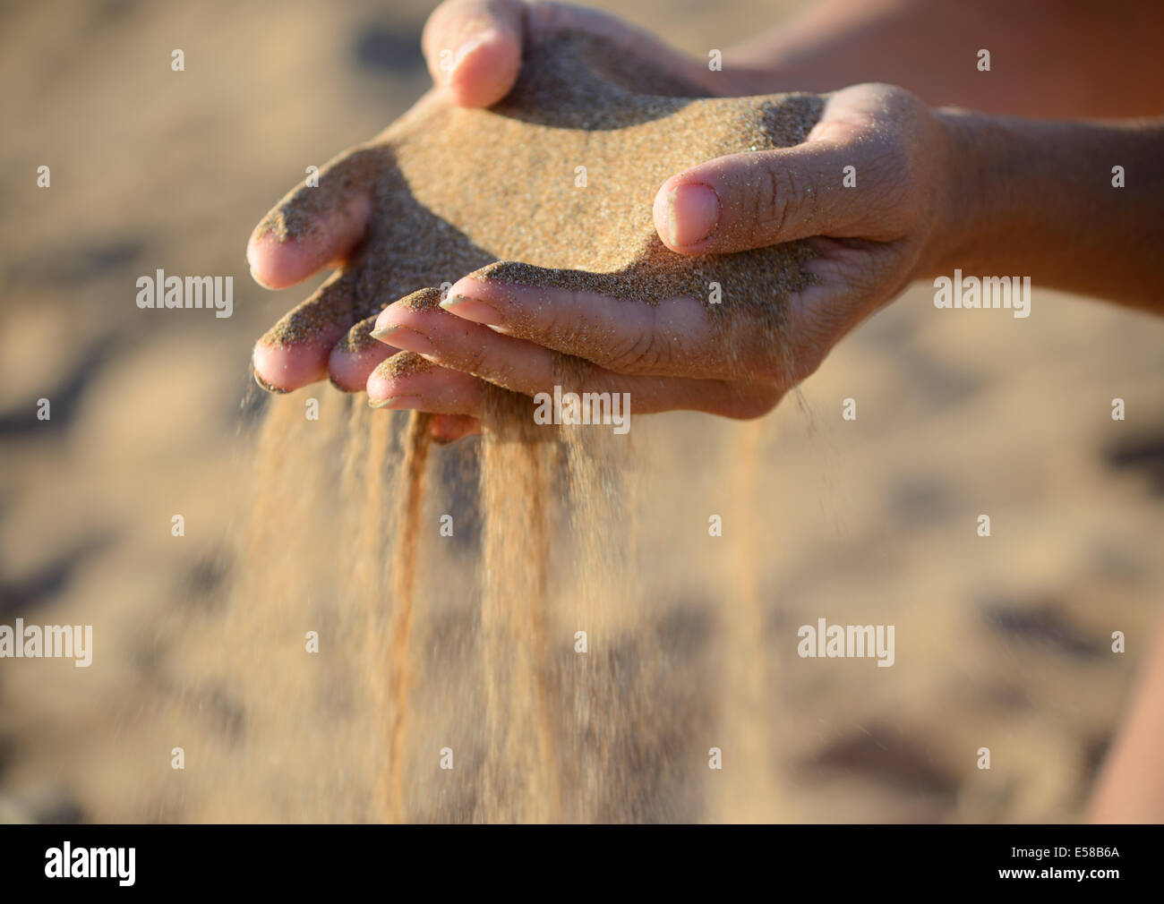 La sabbia si riversa fuori delle mani Foto Stock