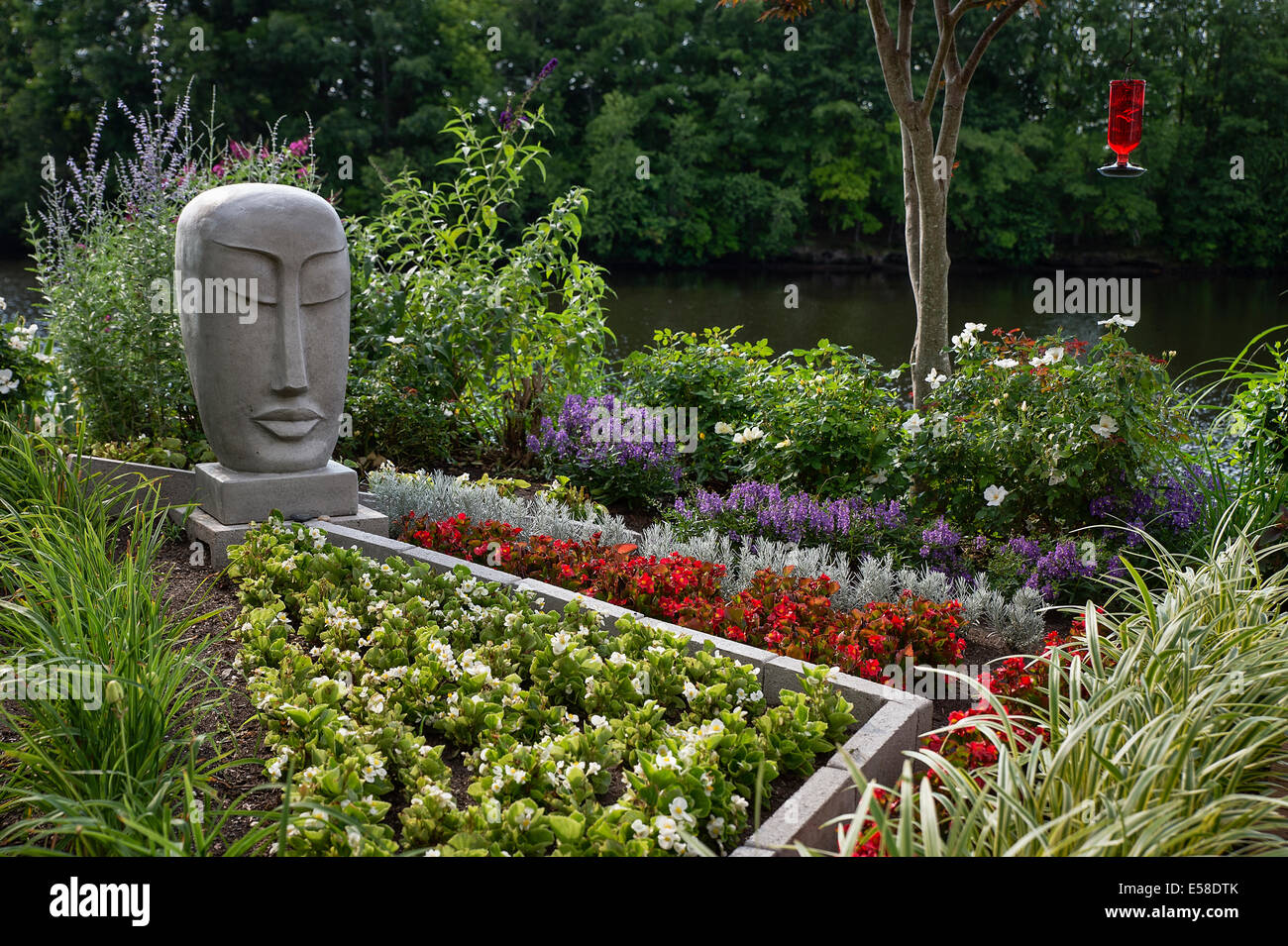 Home flower garden in piena fioritura con la scultura di Buddha. Foto Stock