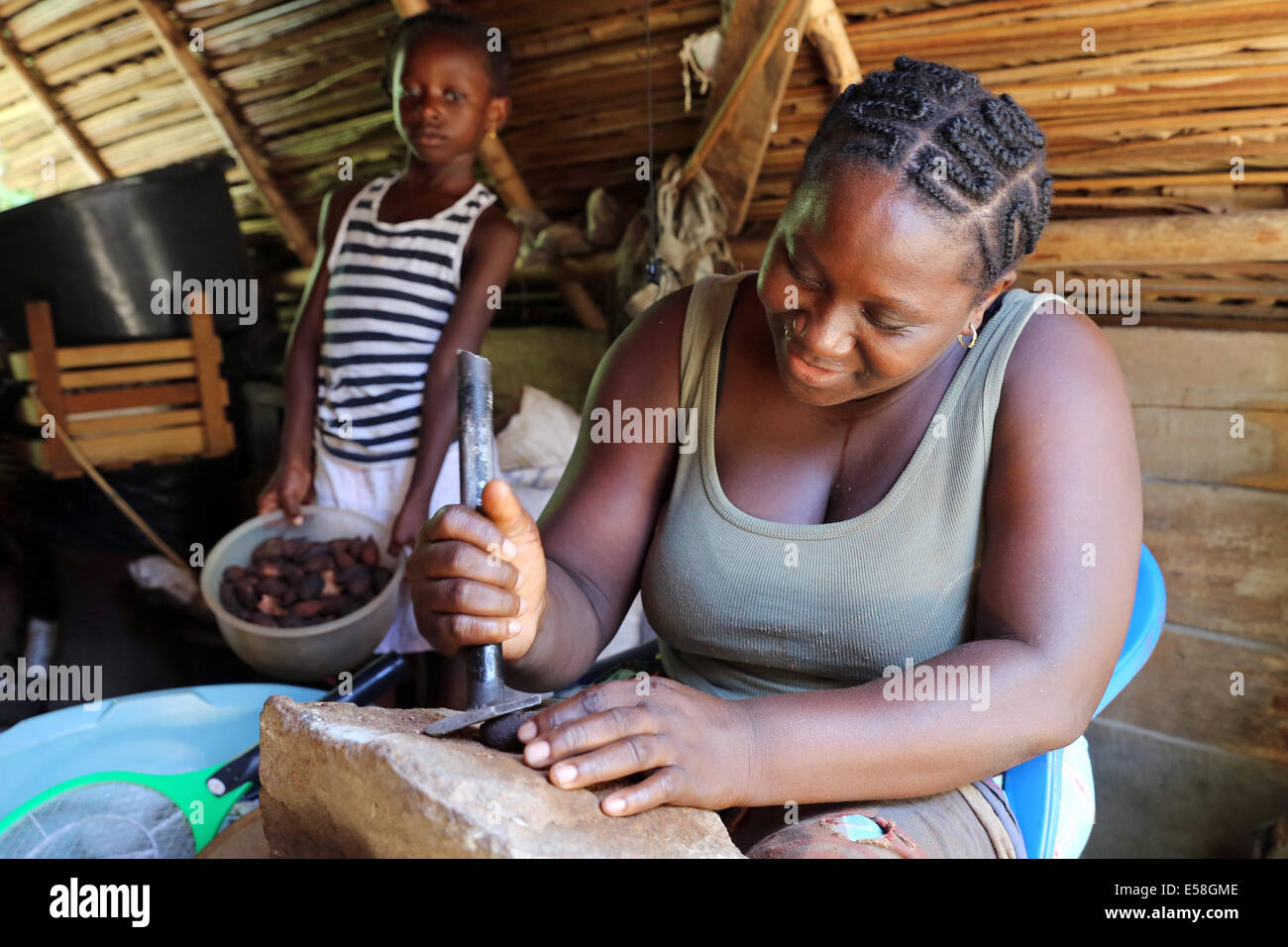 Donna di cracking dadi oleoso per la produzione di cibo, Suriname, America Latina Foto Stock
