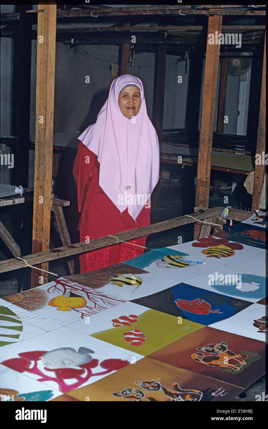 Foto di una donna artista sull'isola di Langkawi Malaysia in piedi nella parte anteriore del dipinto a mano sciarpe di seta in vari stadi Foto Stock