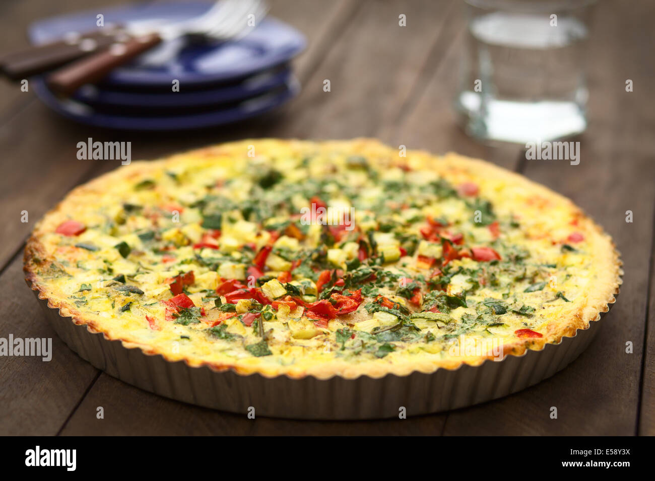 In casa vegetarian quiche con zucchine, il peperone rosso e prezzemolo in una teglia Foto Stock