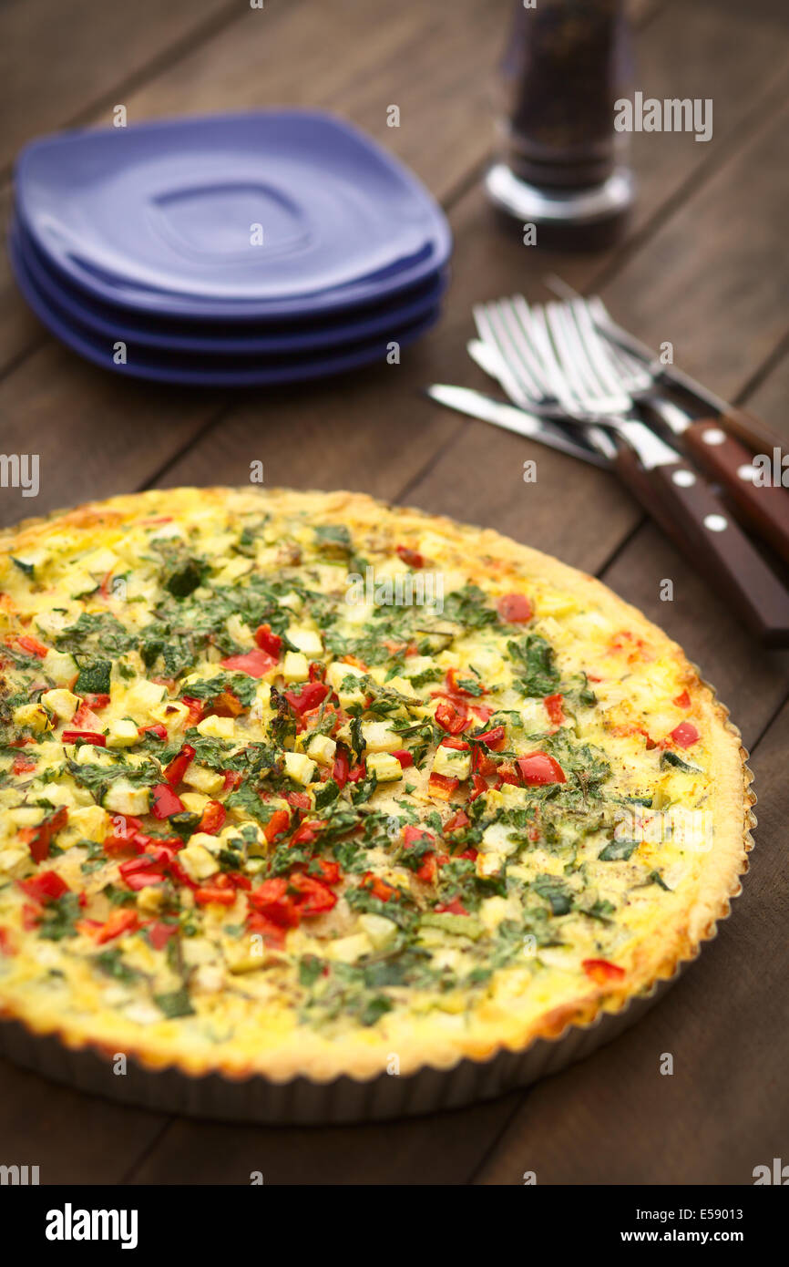 In casa vegetarian quiche con zucchine, il peperone rosso e prezzemolo in una teglia Foto Stock