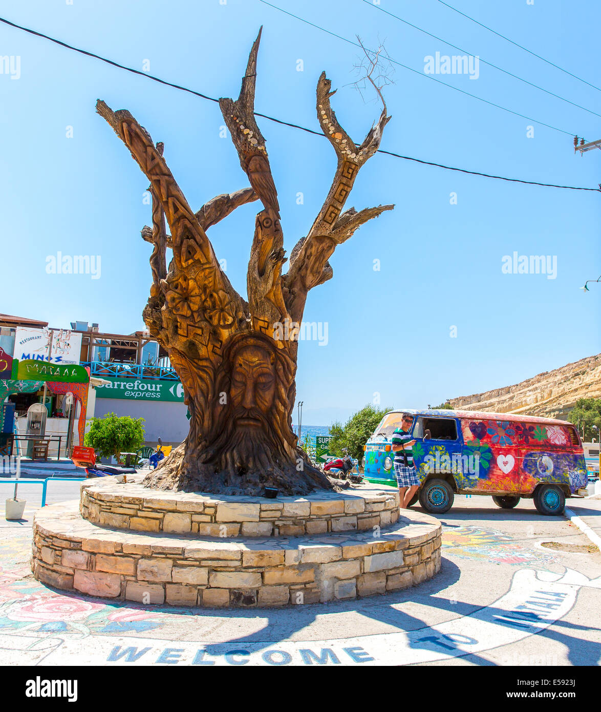 Albero con un volto scolpito sulla piazza di Matala, Grecia Creta. Foto Stock