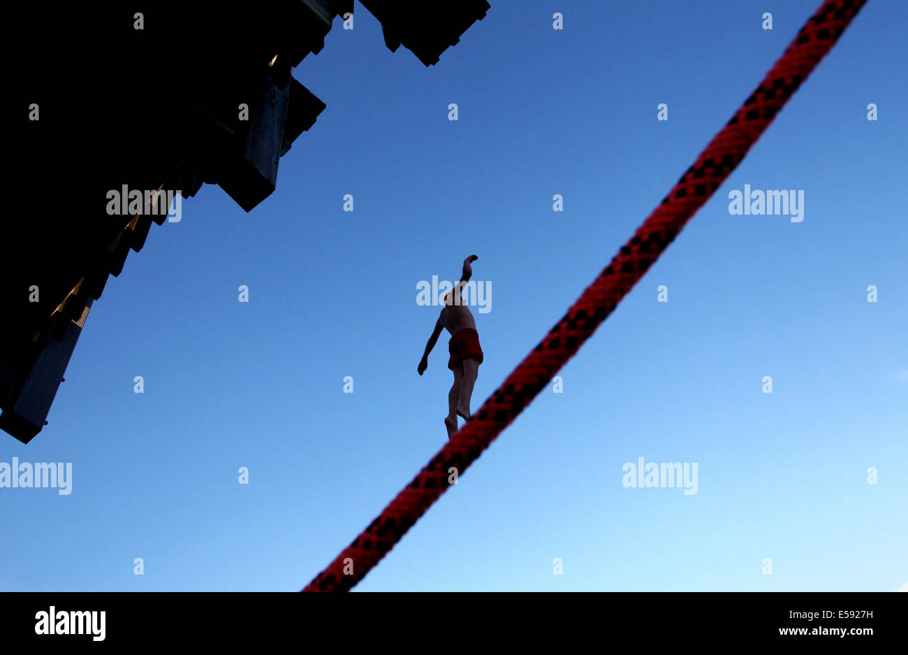 Utting, Germania. 23 Luglio, 2014. Un ragazzo salta da un legno torre immersioni dietro una corda cordon al Lago Ammersee in Utting, Germania, 23 luglio 2014. Foto: KARL-JOSEF HILDENBRAND/dpa/Alamy Live News Foto Stock
