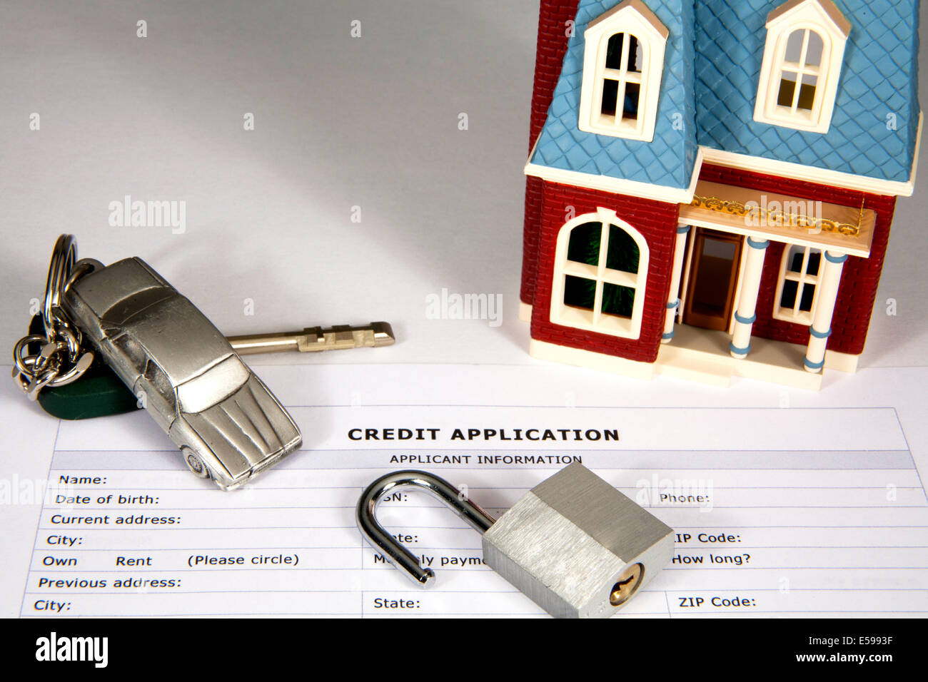 Casa in miniatura e auto con i tasti sulla parte superiore di una domanda di credito con lucchetto aperto Foto Stock