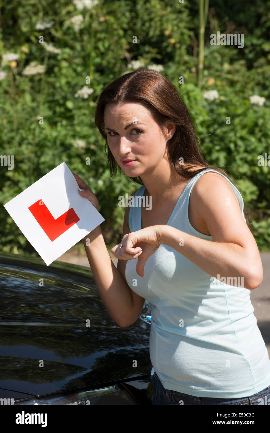 Driver donna tenendo premuto il tasto L e piastra di pollice in giù per un guasto alla guida dei risultati di prova. Foto Stock