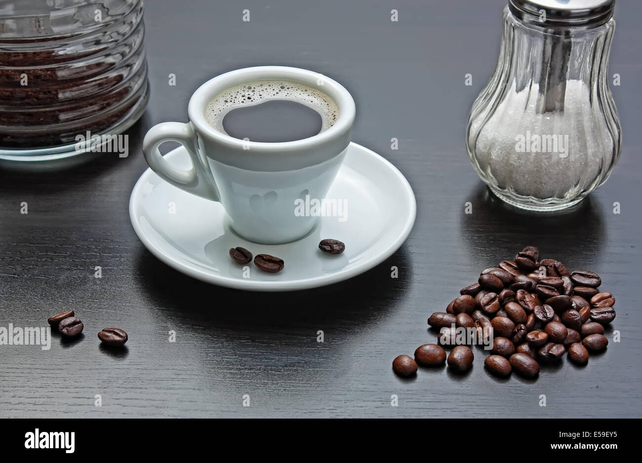 Pila di chicchi di caffè e un bicchiere su un tavolo grigio Foto Stock