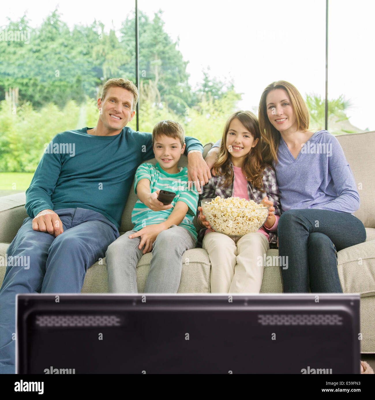 Famiglia di guardare la televisione in salotto Foto Stock