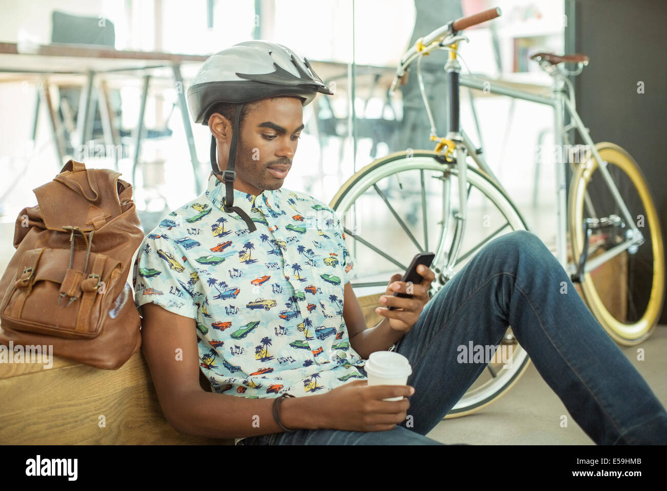 Uomo in bicicletta casco utilizzando il cellulare in ufficio Foto Stock