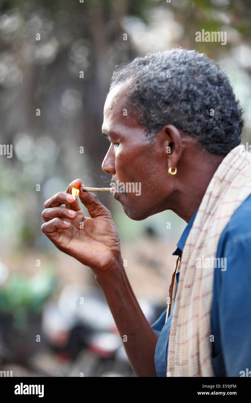 Close-up di un uomo tribali di fumare bidi, un indiano a mano fatte di sigarette di tabacco o beedi foglie, Muriyan Village, Chattisgad Foto Stock