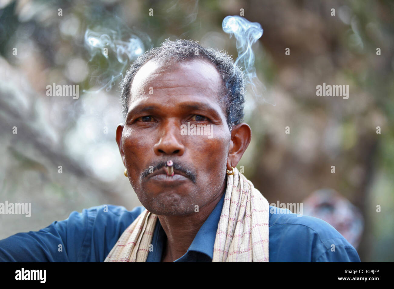Primo piano di un uomo tribale che fuma bidi, una sigaretta indiana fatta a mano di tabacco o foglie di beedi, Muriyan Village, Chattisgad. Facce rurali dell'India Foto Stock