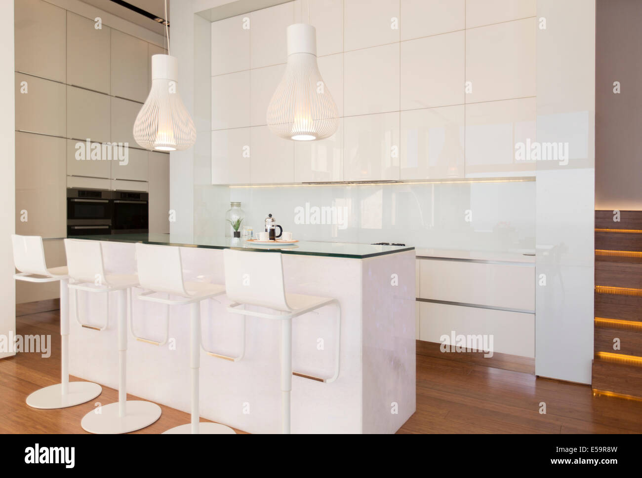 Una nuova, moderna cucina completamente bianca con luci nere appese al  soffitto e sgabelli da bar neri che si siedono al banco per un'area da  pranzo Foto stock - Alamy