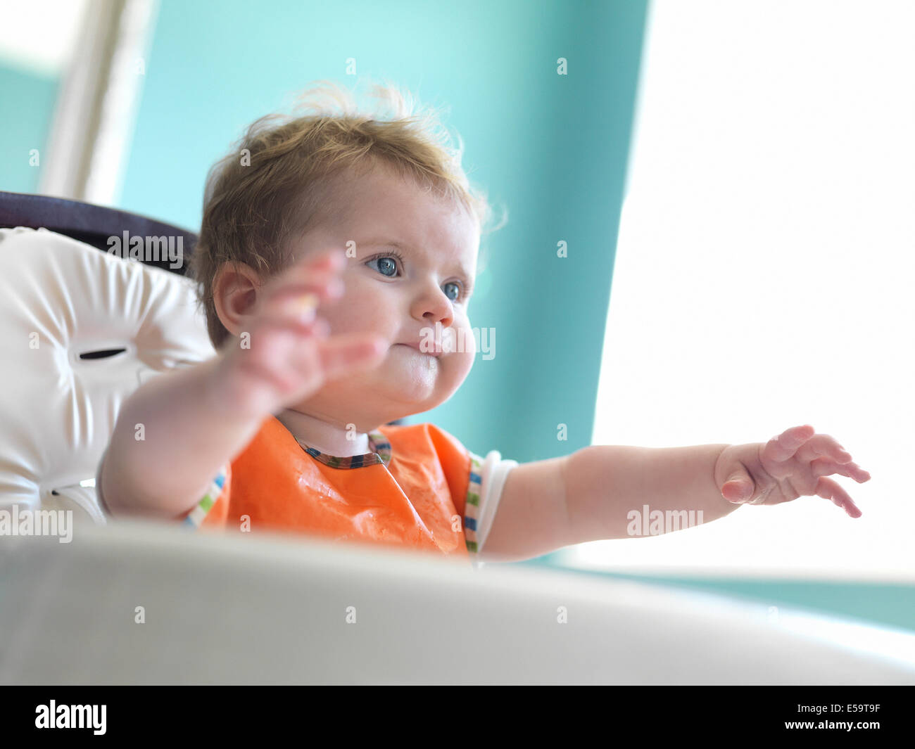 Baby girl raggiungendo fuori dalla poltrona Foto Stock
