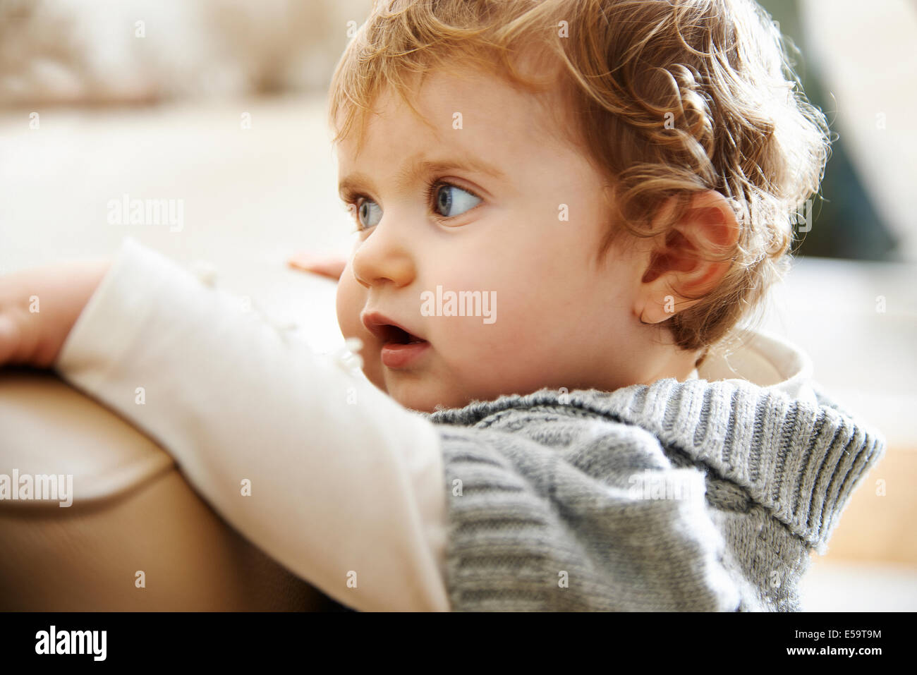 Baby girl aggrappato al bordo del divano Foto Stock