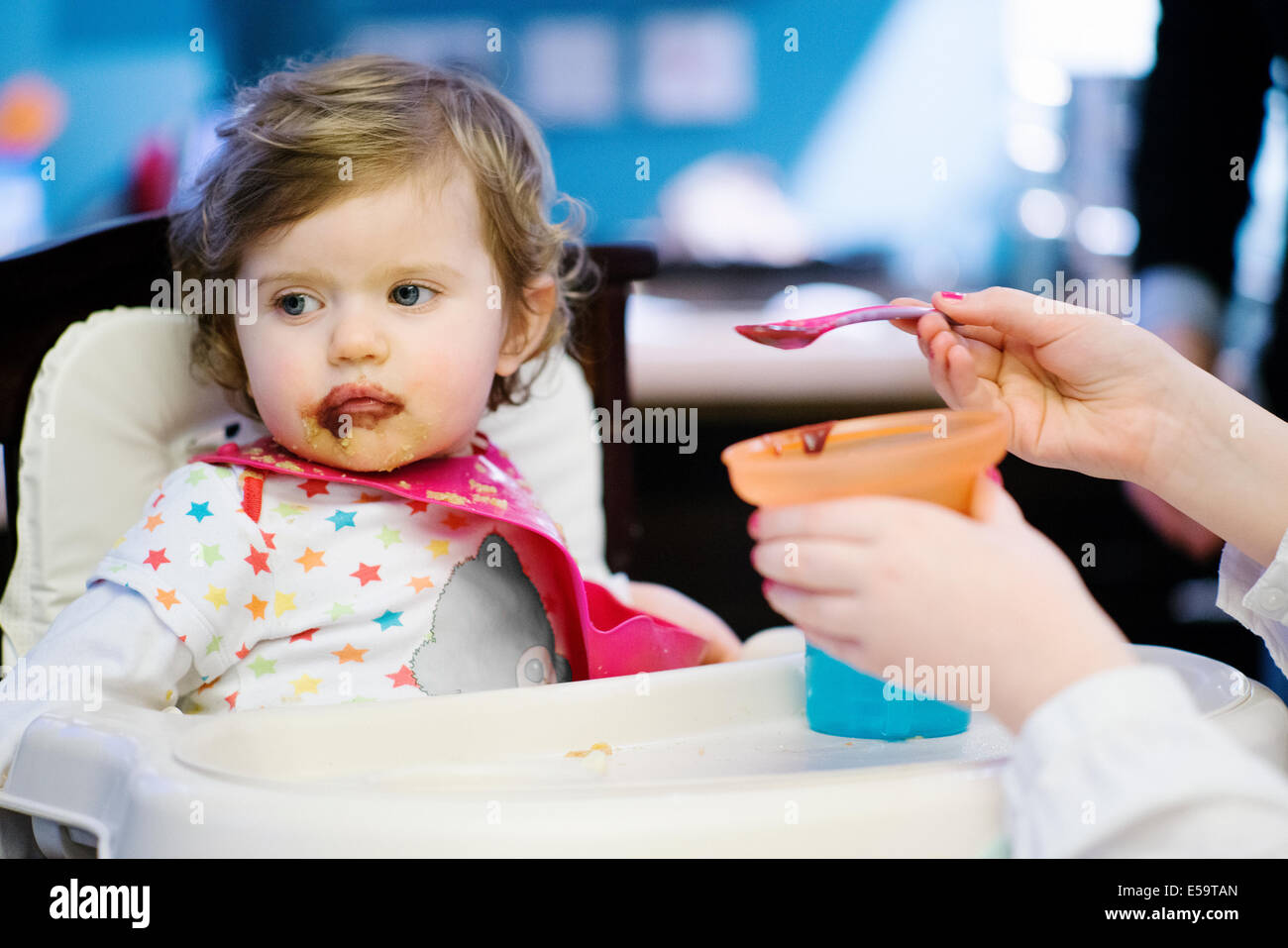 Alimentazione ragazza bambina in sedia alta Foto Stock
