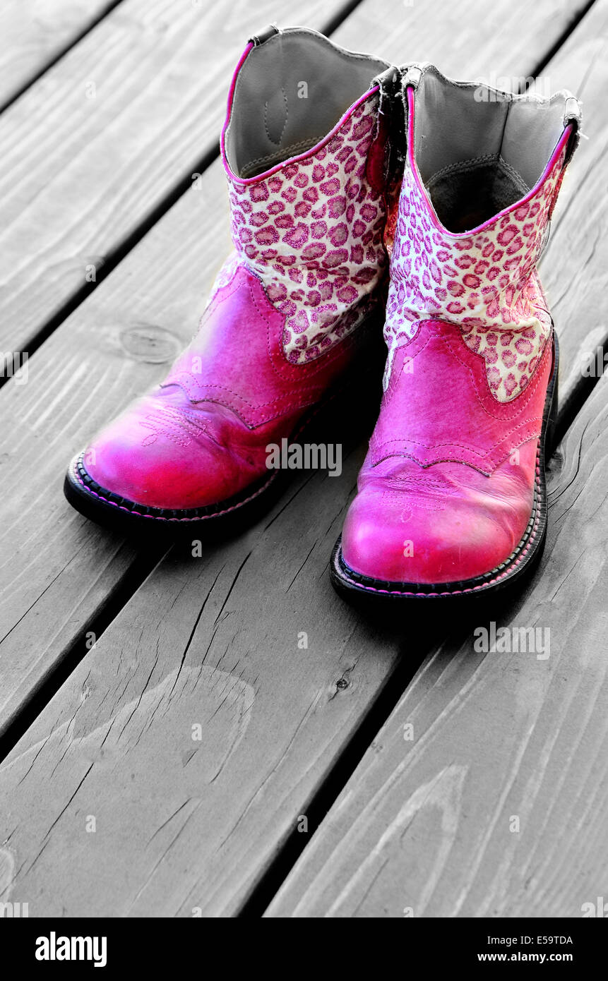 Dettaglio della rosa cowgirl stivali da cowboy sul ponte di legno per una ragazza Foto Stock