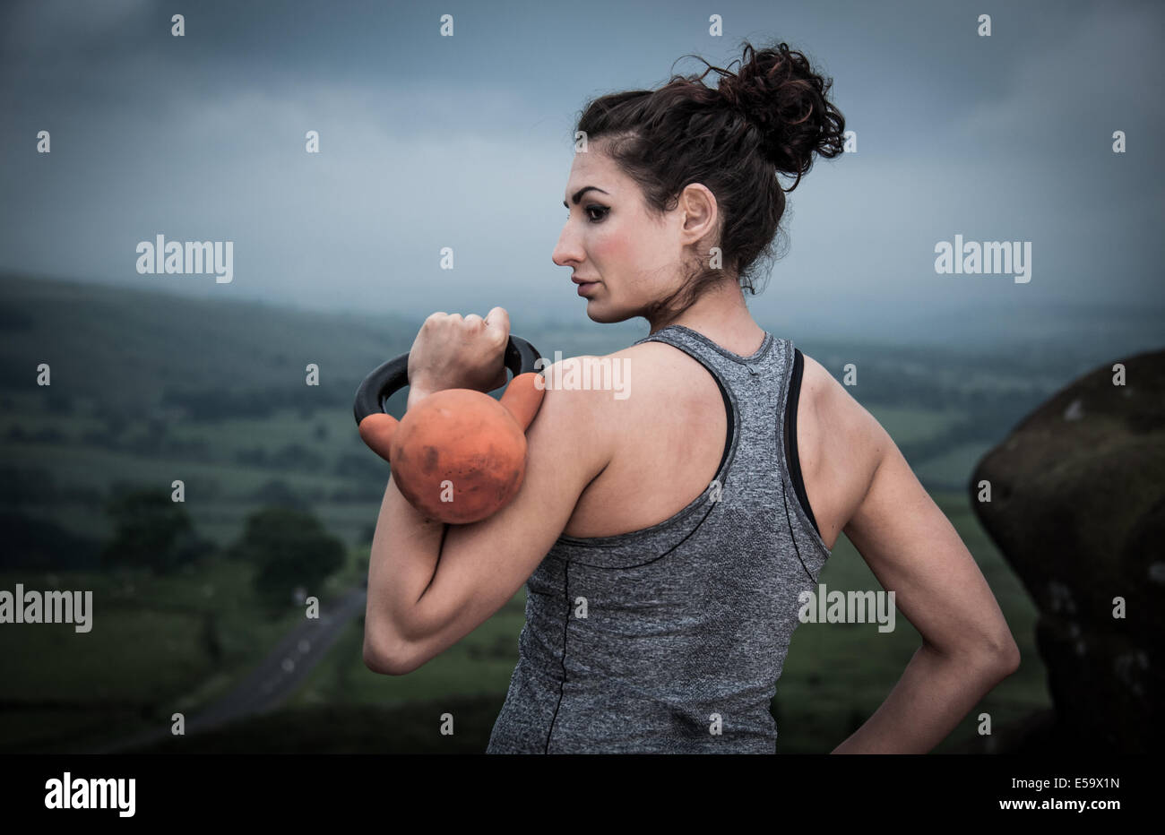 Donna con bollitore bell praticare fitness all'aperto Foto Stock