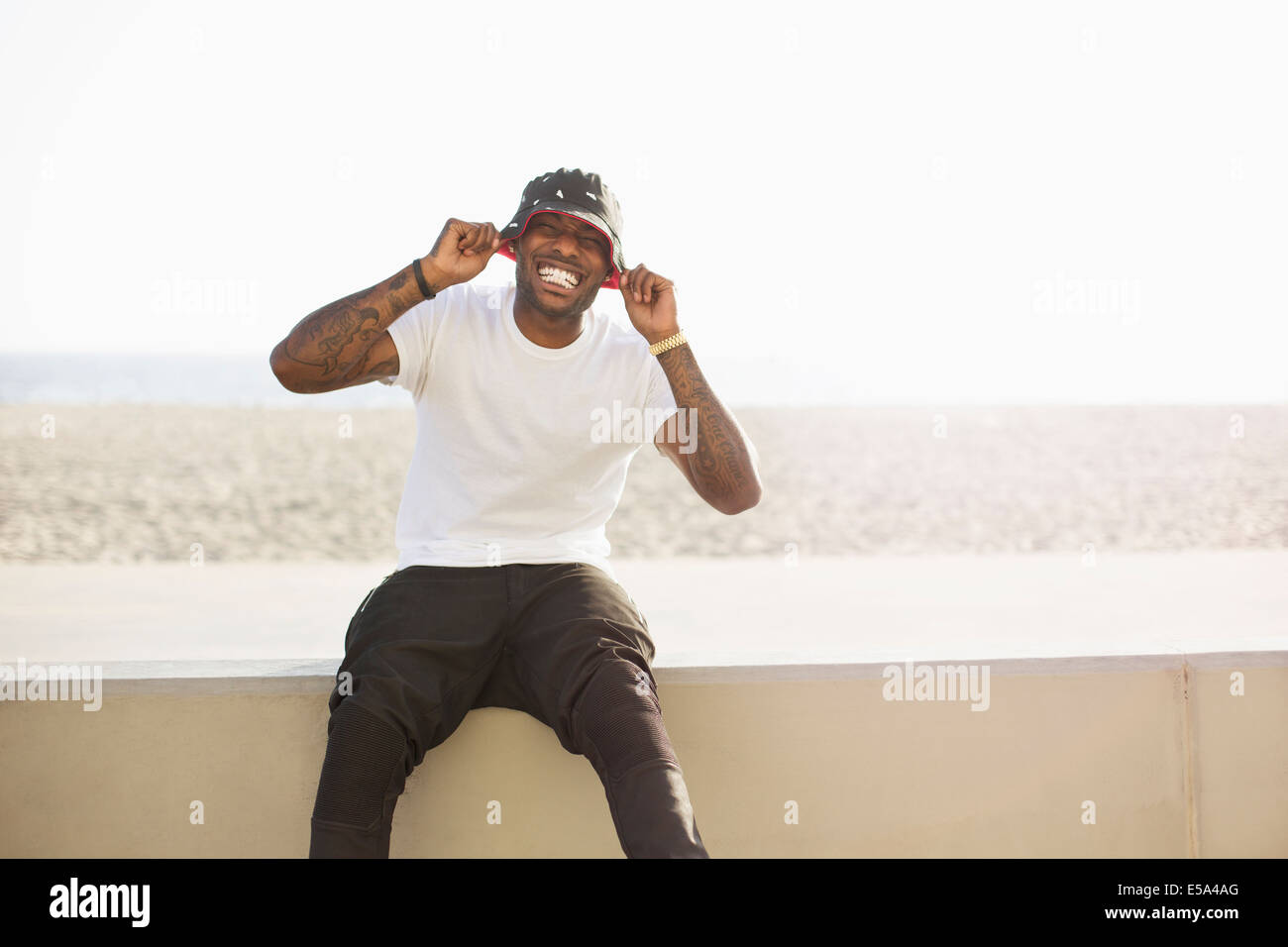 African American uomo sorridente sulla parete di spiaggia Foto Stock