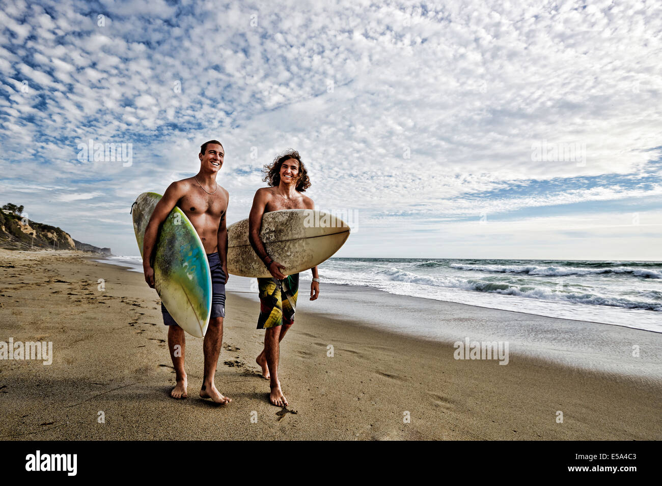 Uomini caucasici che trasportano le tavole da surf in spiaggia Foto Stock