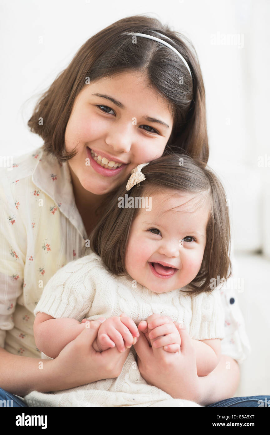 Ragazza ispanica holding toddler sorella in salotto Foto Stock