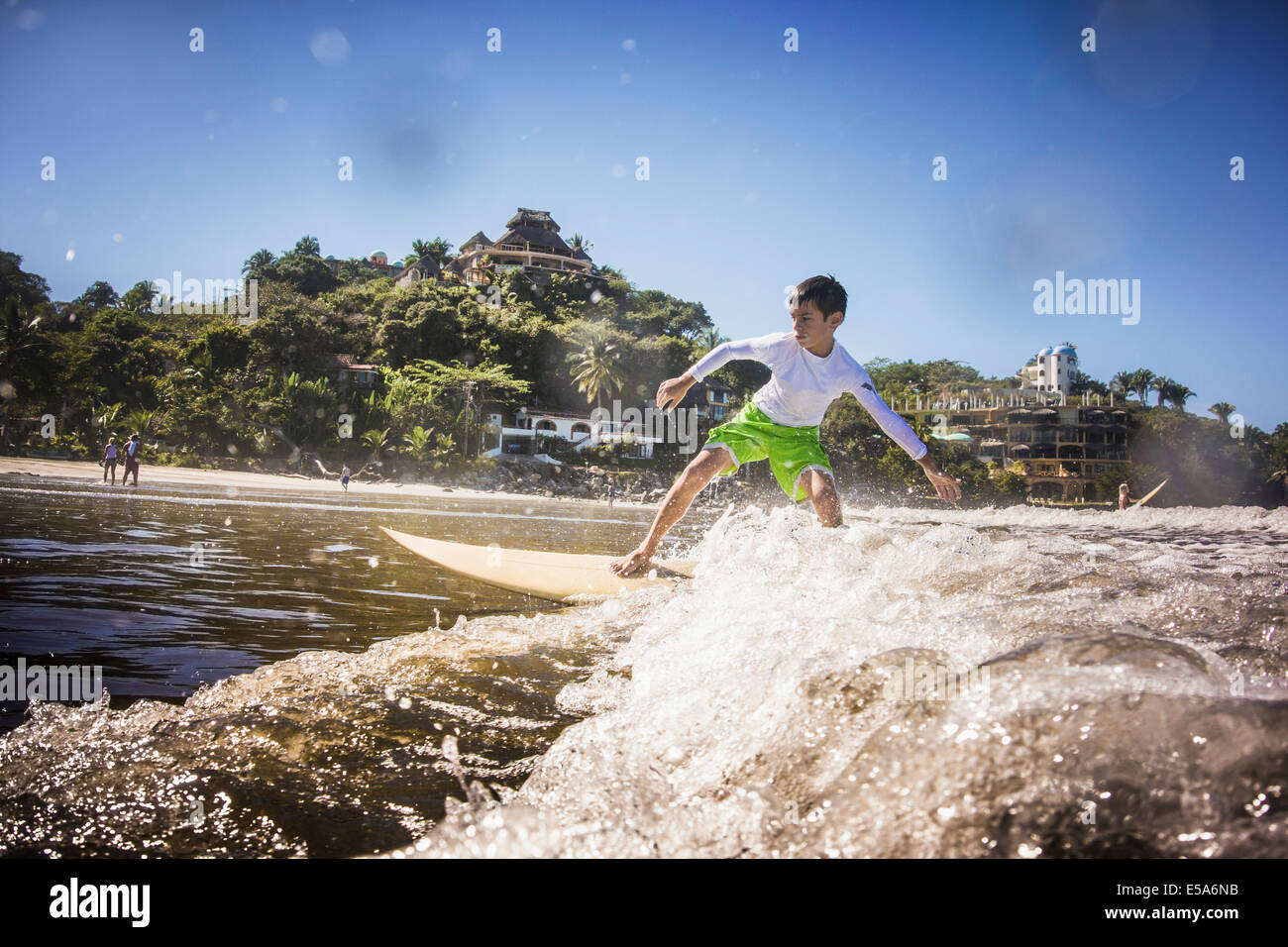 Razza mista boy surf in oceano Foto Stock
