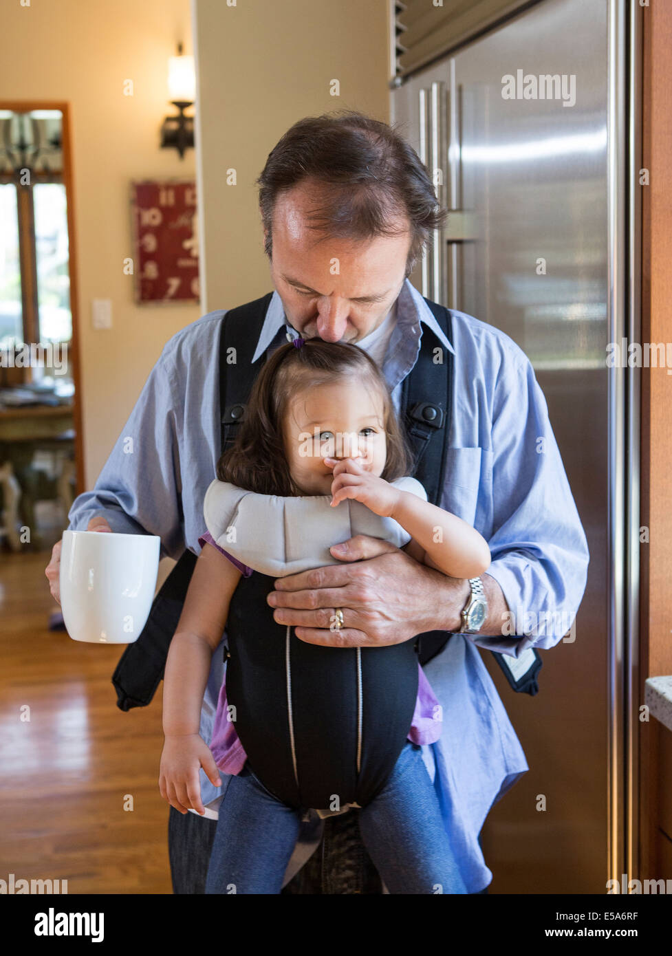 Padre tenendo la figlia a fionda in cucina Foto Stock