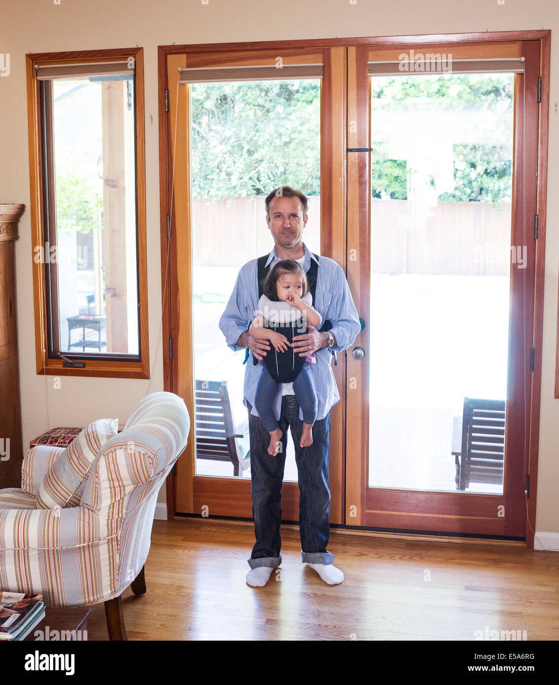 Padre tenendo la figlia a fionda in salotto Foto Stock