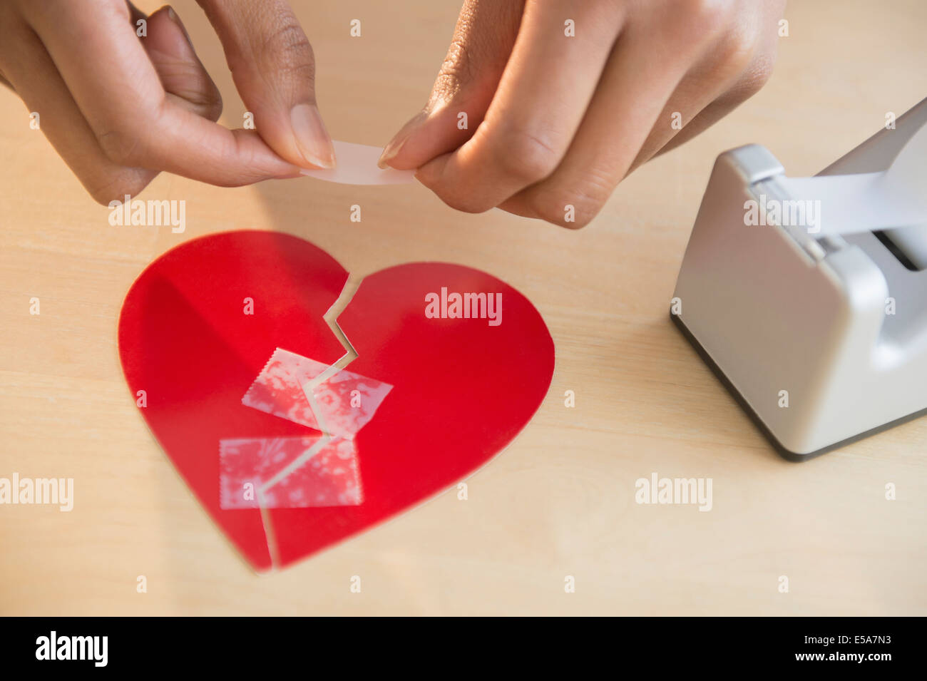 Razza mista donna prendendo rotto cuore di carta Foto Stock
