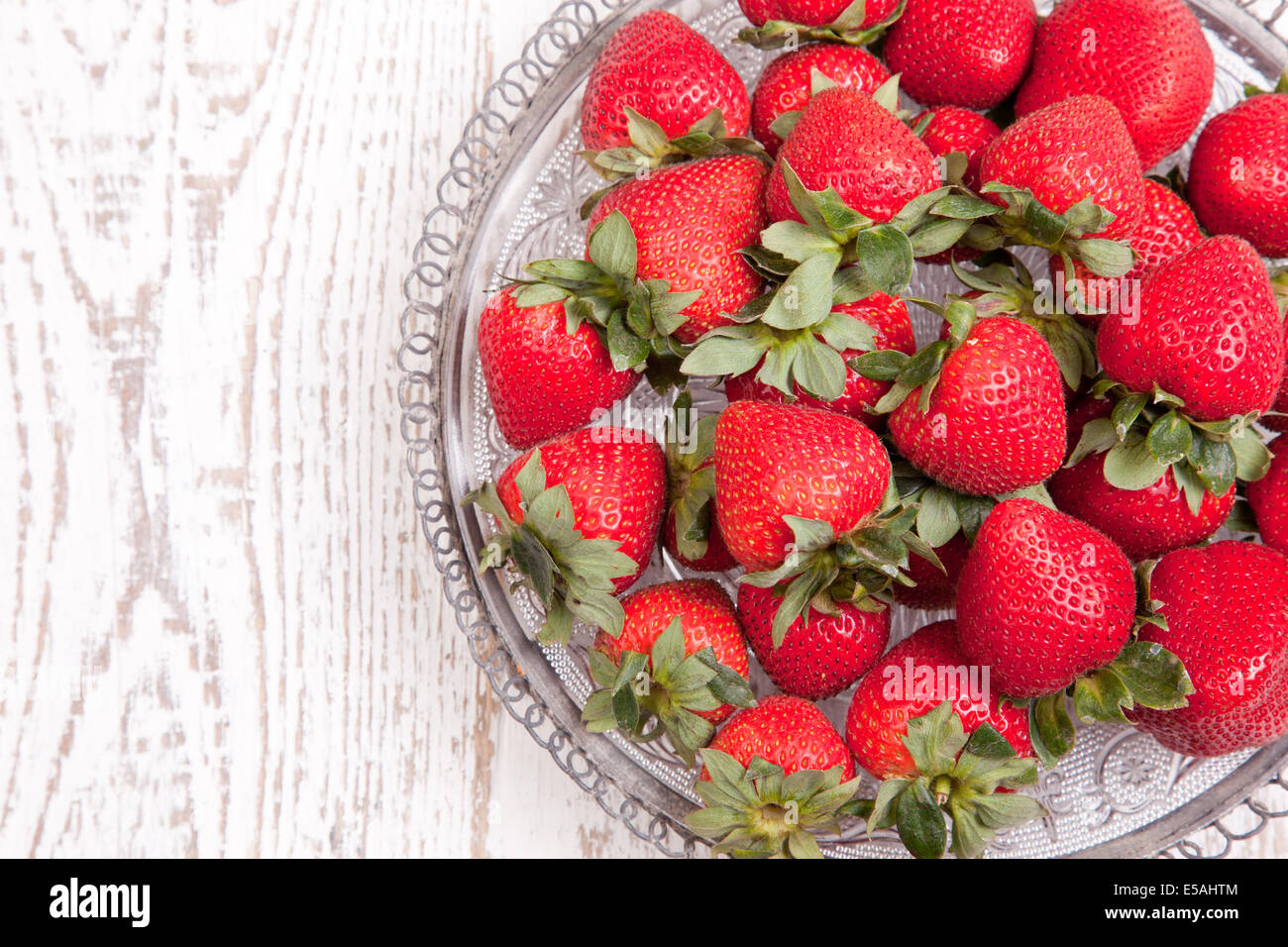 Fragole su bianco invecchiato in legno ciotola vintage. Foto Stock