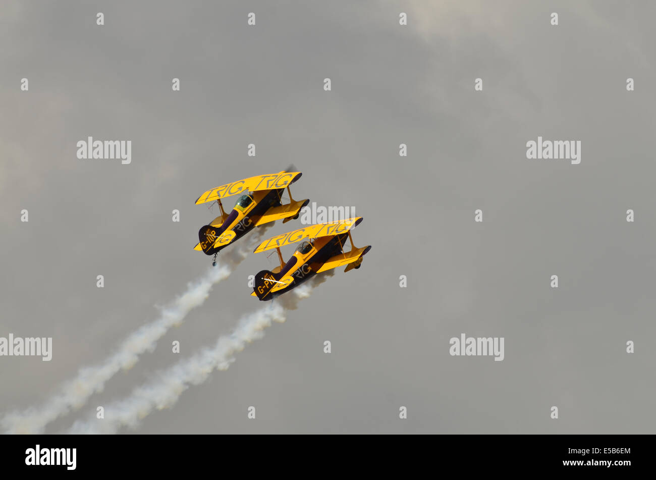 Coppia di stunt bi-aerei contro un grigio scuro cielo emettendo fumo. Foto Stock